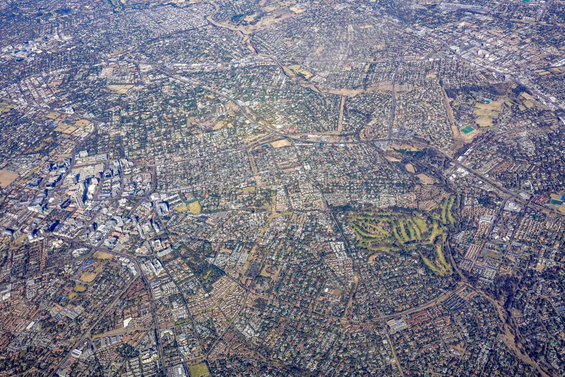 High-altitude aerial view of low-density urban expansion spreading across flat ground.